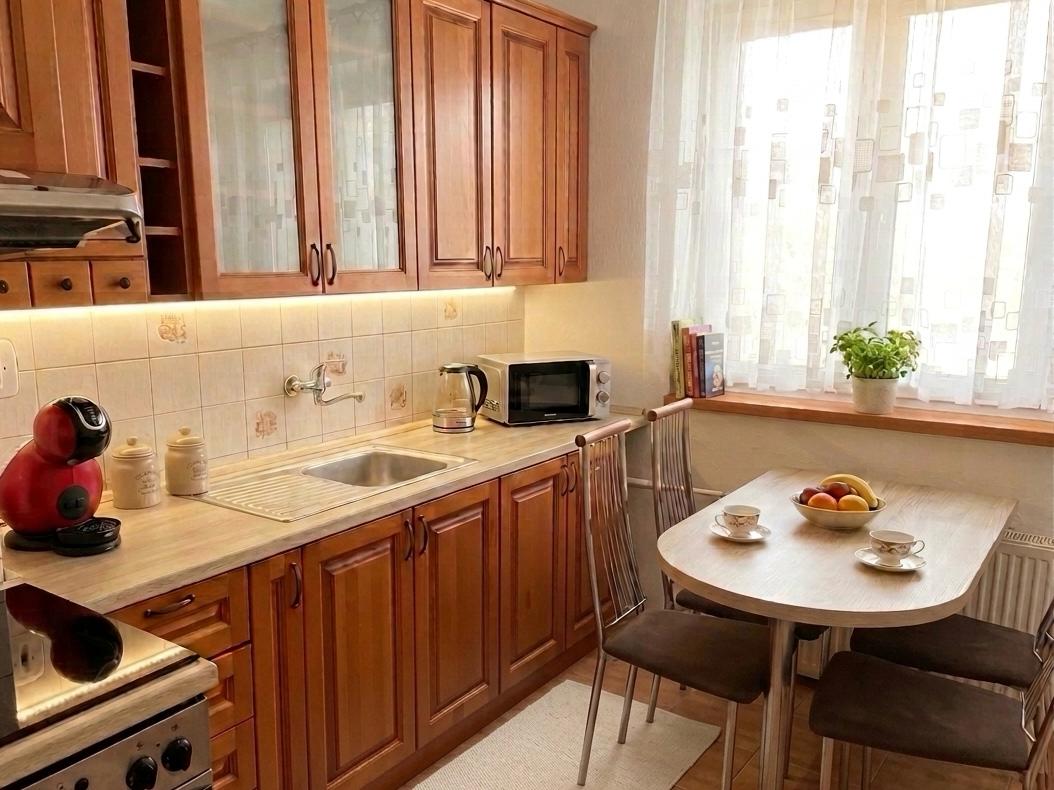 Útulná a plne vybavená kuchyňa vo Ville Sobota v Rimavskej Sobote, s drevenými skrinkami, kávovarom, mikrovlnkou a jedálenským kútom pri okne.